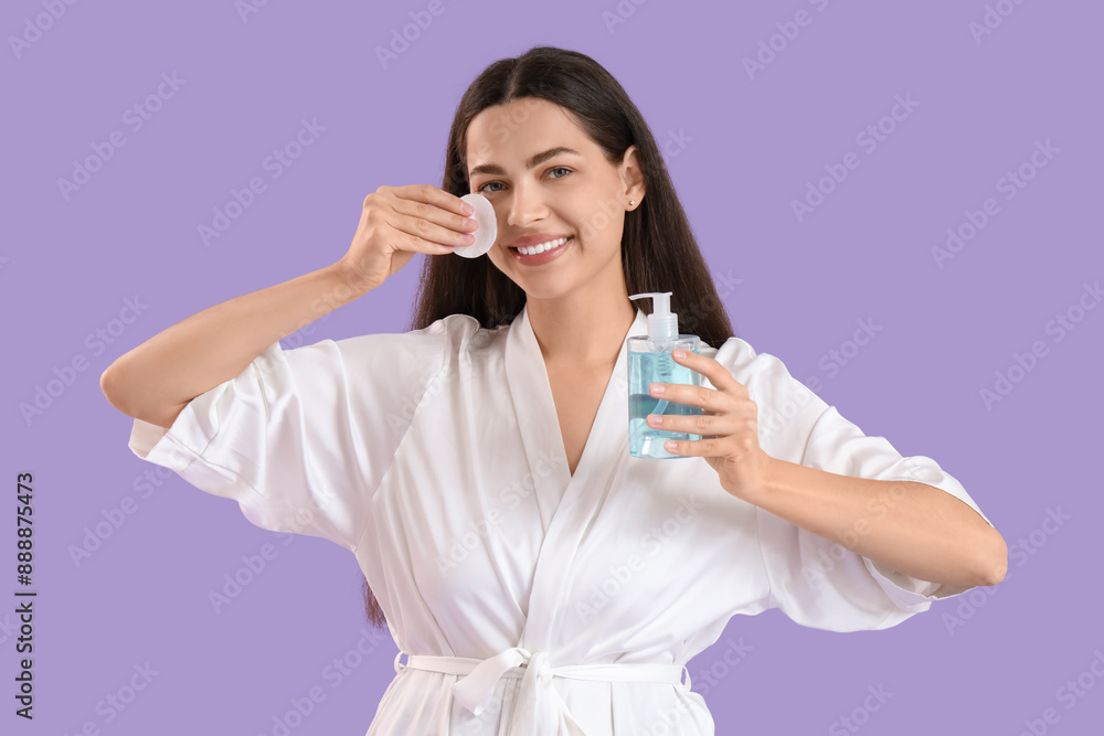 Beautiful young happy woman with cotton pad and bottle of micellar water on purple background Beautiful young happy woman with cotton pad and bottle of micellar water on purple background