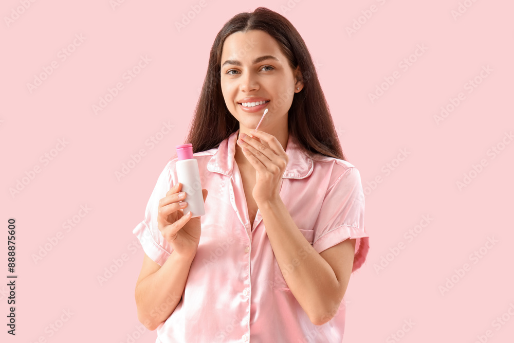 Beautiful young happy woman with cotton bud and bottle of micellar water on pink background Beautiful young happy woman with cotton bud and bottle of micellar water on pink background