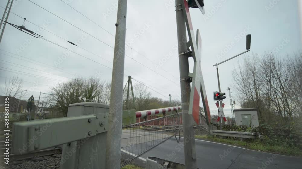 Railroad crossing with barrier down on a cloudy day, signaling the approach of a train, wide angle view Railroad crossing with barrier down on a cloudy day, signaling the approach of a train, wide angle view