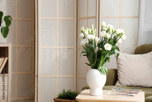 Vase with flowers and magazine on table in stylish living room