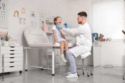 Male pediatrician examining little girl's throat on couch in clinic © Pixel-Shot