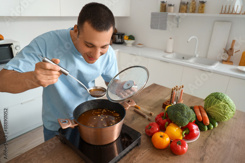 Young man cooking soup at t...
