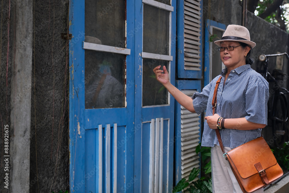 Asian woman going home and knocking the door of her old village house Asian woman going home and knocking the door of her old village house