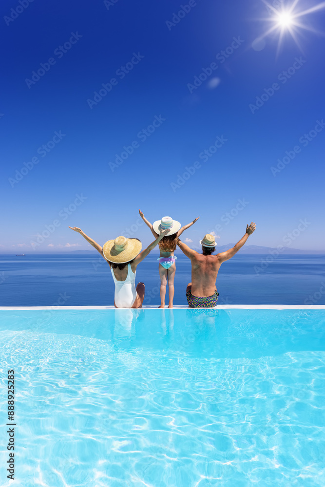 A happy family on summer holidays sits by the swimming pool and enjoys the beautiful view