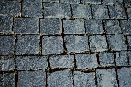 The texture of dark paving stones. Top view of the cobblestone pavement. An old stone sidewalk. The texture of the paving stones. The background is made of cobblestones, the road is made of cobbleston photo