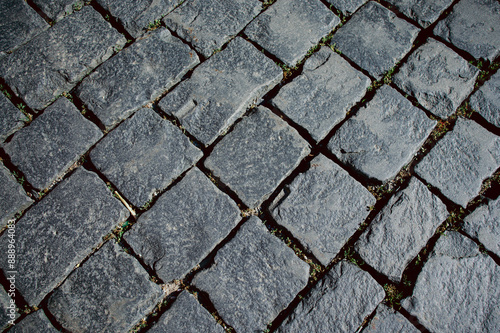 The texture of dark paving stones. Top view of the cobblestone pavement. An old stone sidewalk. The texture of the paving stones. The background is made of cobblestones, the road is made of cobbleston photo