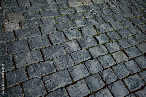 The texture of dark paving stones. Top view of the cobblestone pavement. An old stone sidewalk. The texture of the paving stones. The background is made of cobblestones, the road is made of cobbleston photo