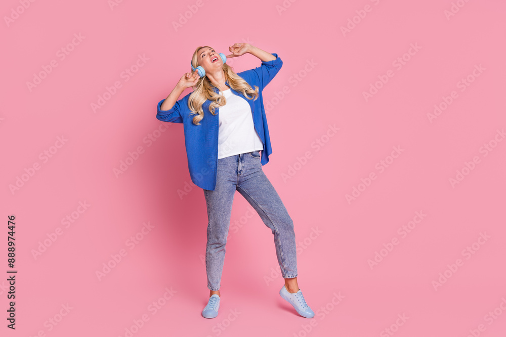 Full size photo of nice woman with wavy hair dressed blue shirt dancing in headphones enjoy pop playlist isolated on pink color background Full size photo of nice woman with wavy hair dressed blue shirt dancing in headphones enjoy pop playlist isolated on pink color background