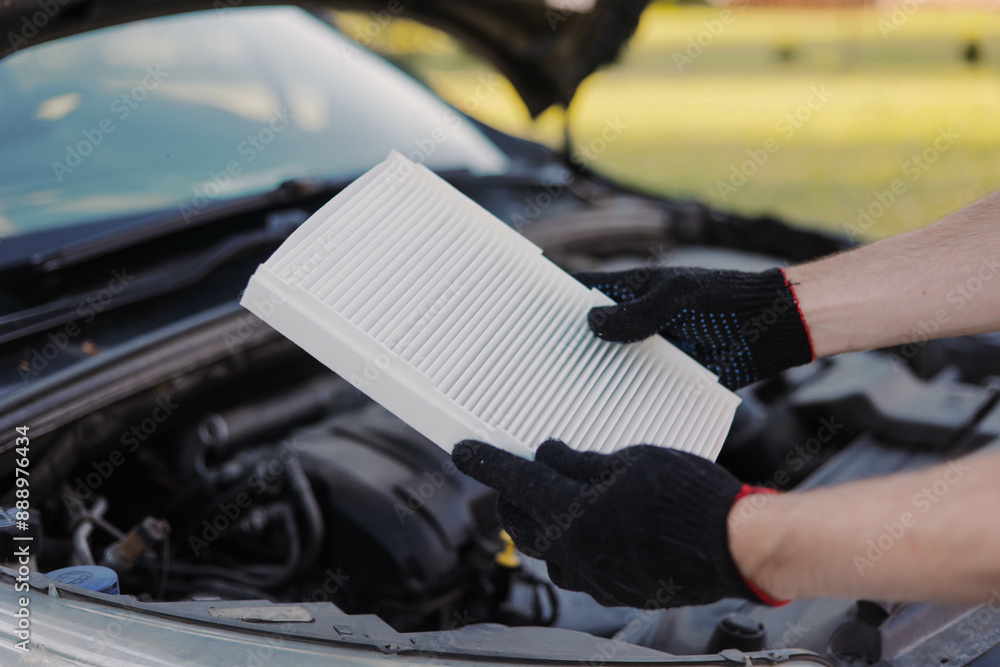 Auto mechanic holds a new car cabin air filter to replace the old filter. Auto mechanic holds a new car cabin air filter to replace the old filter.