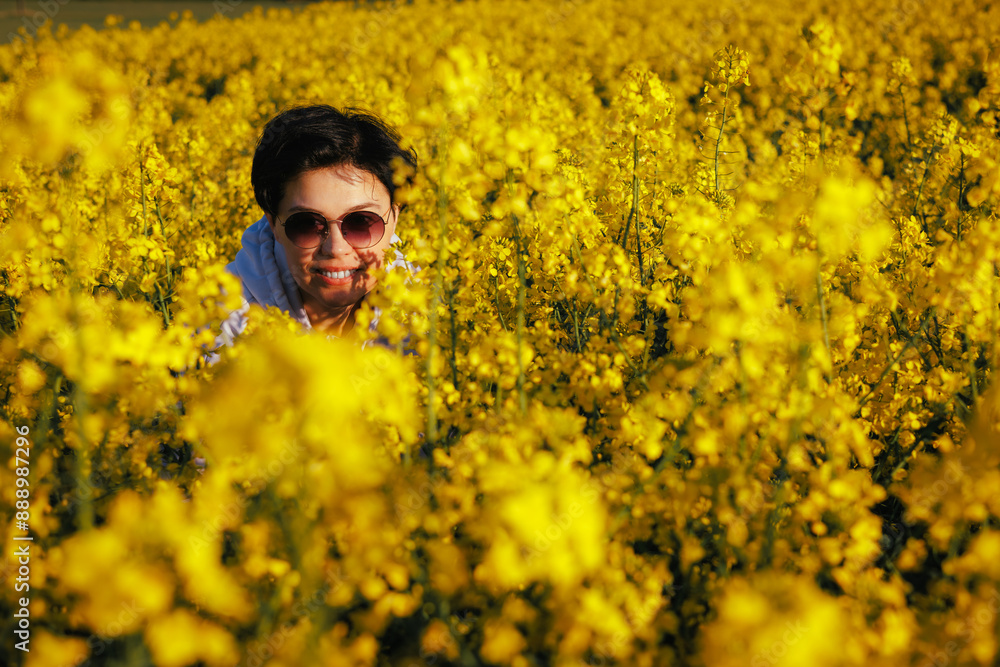 Smiling middle-aged woman in a rapeseed field in the rays of the setting sun. Smiling middle-aged woman in a rapeseed field in the rays of the setting sun.