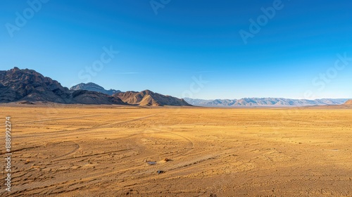 A desert landscape with a clear blue sky. The sky is dotted with clouds, and the sun is shining brightly. The emptiness of the desert gives a sense of solitude and vastness