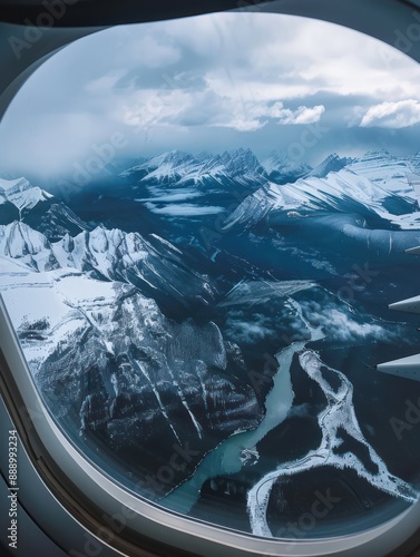 Breathtaking aerial view of Rocky Mountains towering peaks blanketed in snow, ice, contrasting against clear blue sky. Winding river flows through heart of mountains, white waters reflecting photo