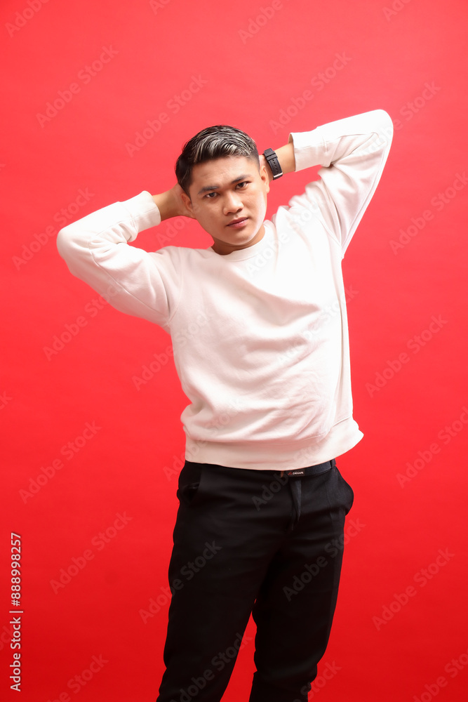 Fototapeta premium mature Asian man wearing a white sweater standing elegantly with both hands holding the back of his head. for fashion content, advertising, business