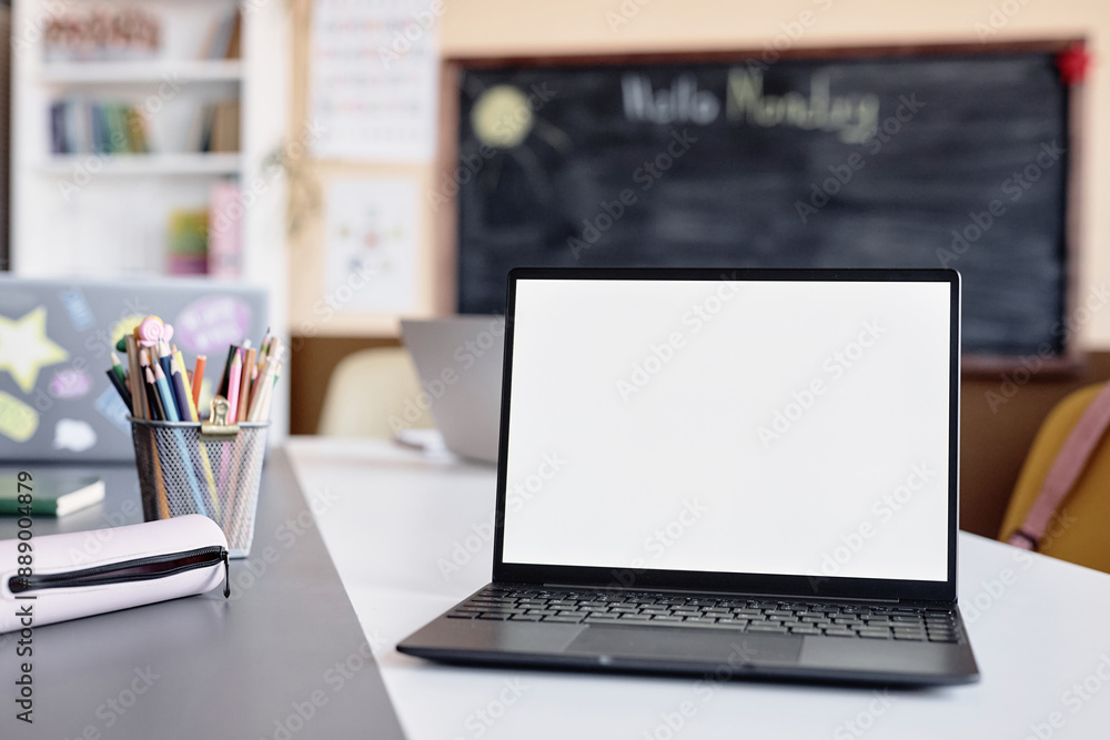 © Seventyfour - Background shot of laptop empty mockup screen on table in front of camera in primary school classroom, copy space