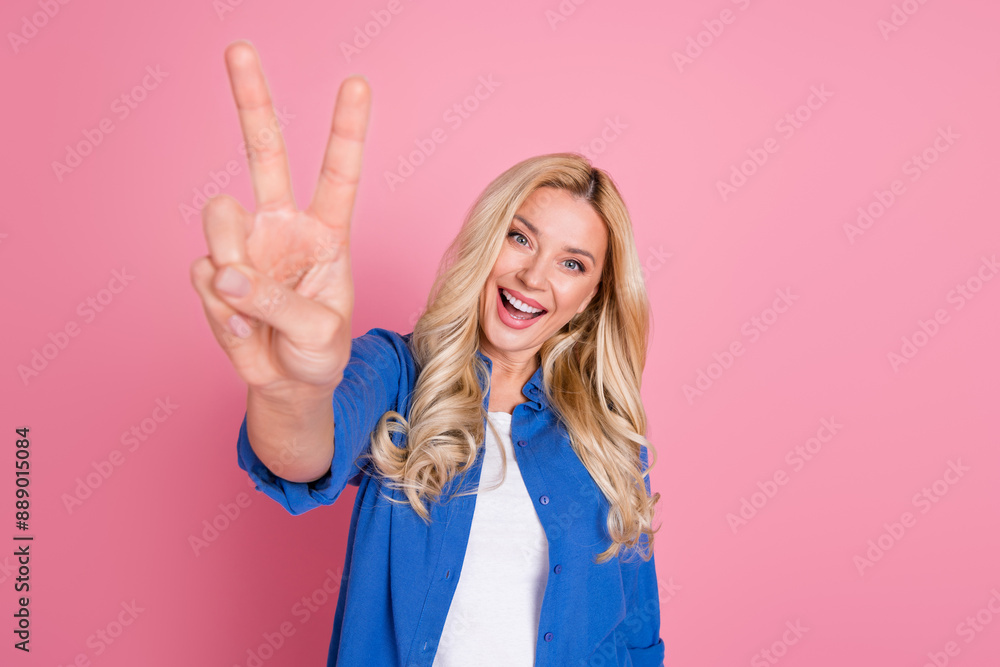 Photo of charming positive woman wear blue shirt showing you v-sign empty space isolated pink color background Photo of charming positive woman wear blue shirt showing you v-sign empty space isolated pink color background