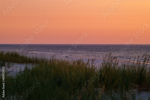 Obraz na płótnie Beautiful orange sky over the sea. Blurry grass in the foreground. Beautiful sandy beach. Golden hour. Baltic Sea, Slajszewo, Poland w salonie