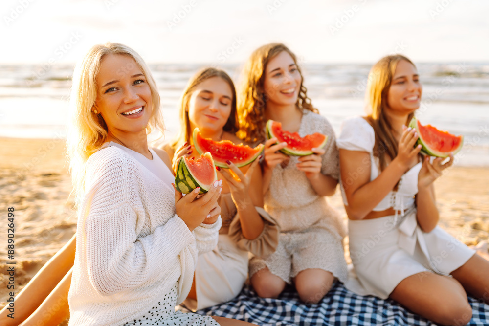 The company of female friends having fun and enjoying a summer picnic and eating a watermelon with the sea in the background. Bachelorette. People, lifestyle, travel, nature and vacations concept. The company of female friends having fun and enjoying a summer picnic and eating a watermelon with the sea in the background. Bachelorette. People, lifestyle, travel, nature and vacations concept.