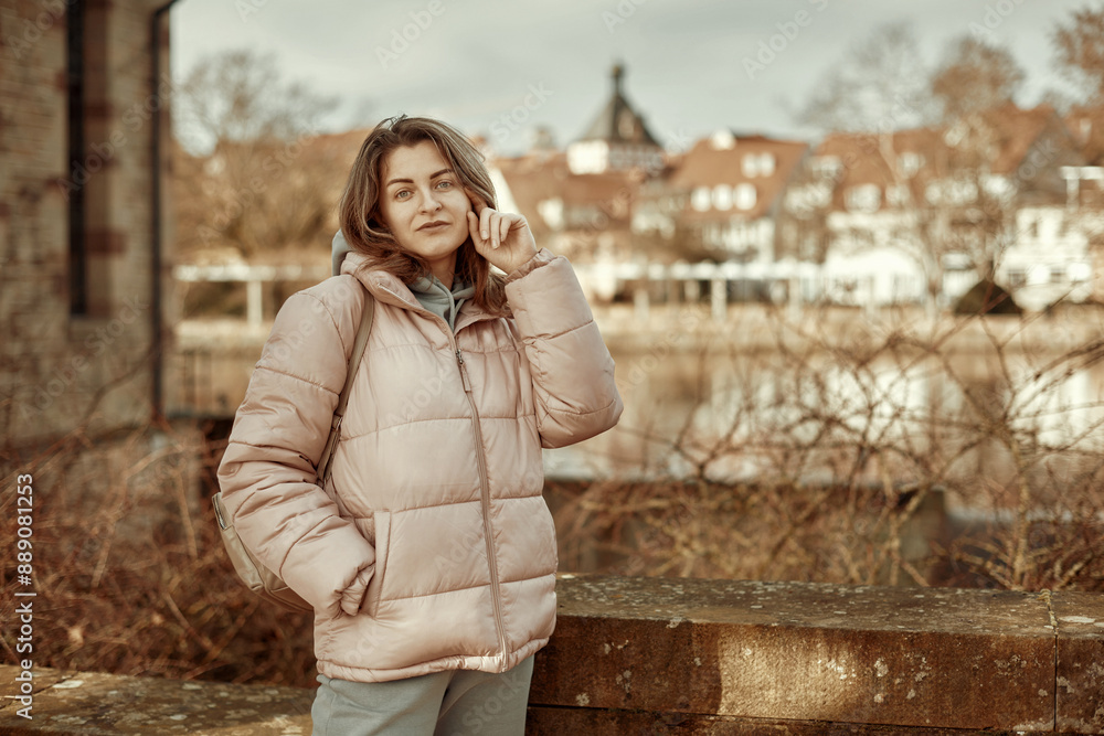 Young beautiful pretty tourist girl in warm hat and coat with backpack walking at cold autumn in Europe city enjoying her travel in Bietigheim-Bissingen, Deutschland. Young beautiful pretty tourist girl in warm hat and coat with backpack walking at cold autumn in Europe city enjoying her travel in Bietigheim-Bissingen, Deutschland.