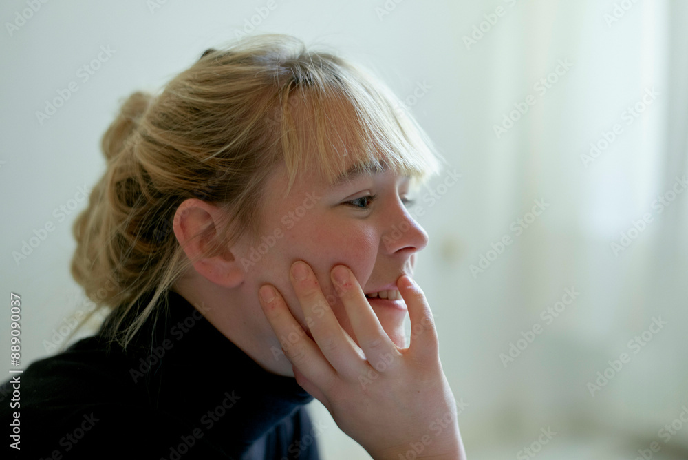 Smiling woman with blond hair in a messy bun resting her chin on her hand, looking away thoughtfully. Smiling woman with blond hair in a messy bun resting her chin on her hand, looking away thoughtfully.