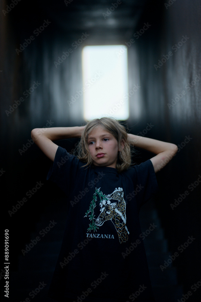 Young girl with hands behind head standing in a dark corridor lit by natural light at the end. Young girl with hands behind head standing in a dark corridor lit by natural light at the end.