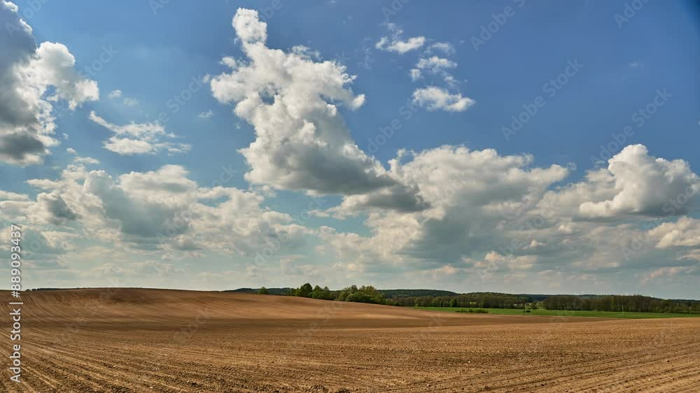 A timelapse of clouds over an agricultural field. White fluffy clouds over a plowed field. The natural landscape in the countryside. A timelapse of clouds over an agricultural field. White fluffy clouds over a plowed field. The natural landscape in the countryside.