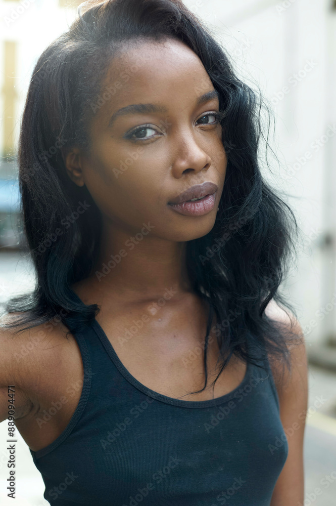 Young woman with long black hair wearing a black tank top, posing confidently on an urban street. Young woman with long black hair wearing a black tank top, posing confidently on an urban street.