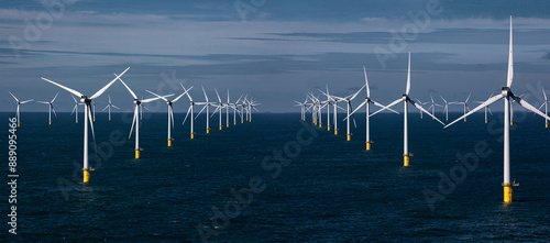 Offshore wind farm with rows of wind turbines in the ocean under a cloudy sky. photo