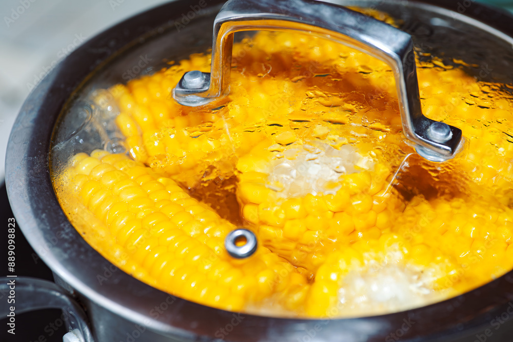 Pot of corn is boiling on a stove. The corn is yellow and he is cooked