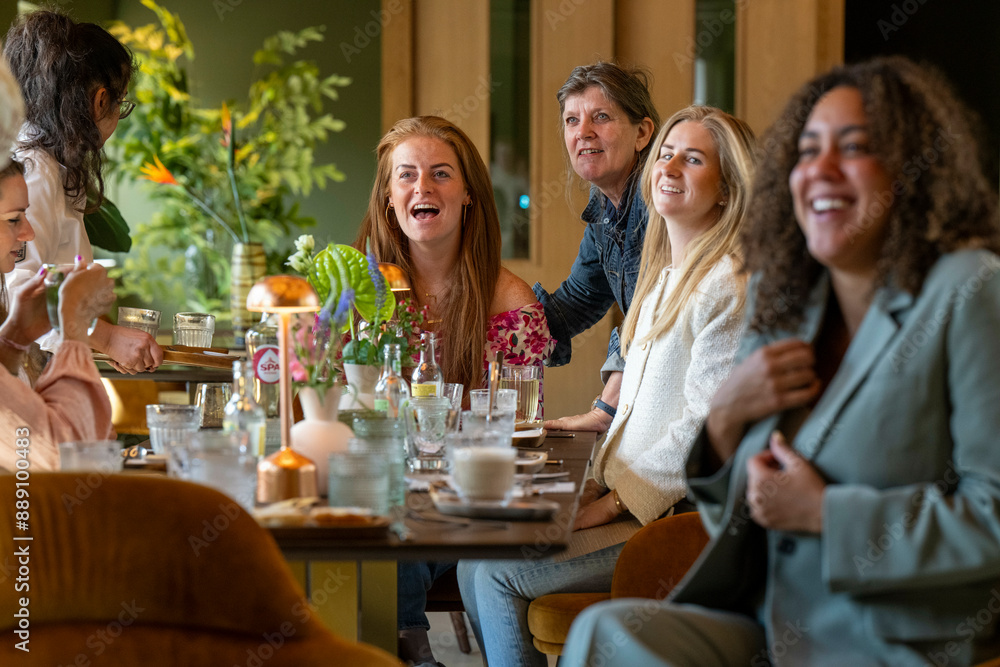 Group of women enjoying a laughter-filled meal together at a cozy restaurant. Group of women enjoying a laughter-filled meal together at a cozy restaurant.