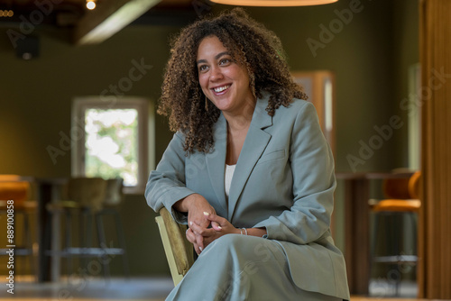 Confident young woman in a stylish suit sitting with a smile in a modern office setting. photo