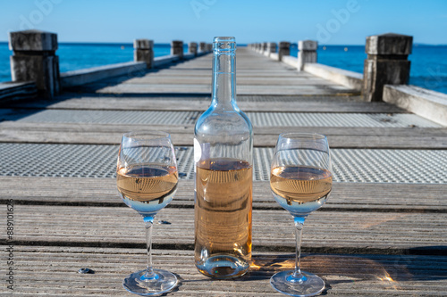 Tasting of cold rose wine from Provence outdoor on wooden yacht pier with view on blue water and white sandy beach Plage de Pampelonne near Saint-Tropez, summer vacation in France photo