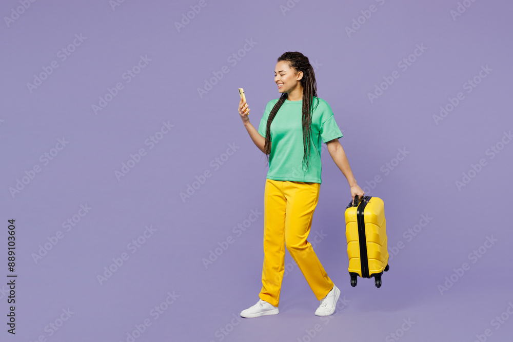 Traveler woman wear green casual clothes hold suitcase bag use mobile cell phone isolated on plain purple background . Tourist travel abroad in free time rest getaway Air flight trip journey concept Traveler woman wear green casual clothes hold suitcase bag use mobile cell phone isolated on plain purple background . Tourist travel abroad in free time rest getaway Air flight trip journey concept