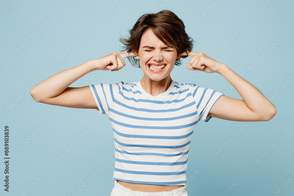 Young sad woman wears striped t-shirt casual clothes cover ears with hands fingers do not want to listen scream isolated on plain pastel light blue cyan background studio portrait. Lifestyle concept. Young sad woman wears striped t-shirt casual clothes cover ears with hands fingers do not want to listen scream isolated on plain pastel light blue cyan background studio portrait. Lifestyle concept.