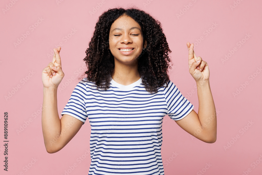 Little kid teen girl wears blue striped t-shirt casual clothes wait special moment, keep fingers crossed, making wish, eyes closed isolated on plain pastel pink background Childhood lifestyle concept Little kid teen girl wears blue striped t-shirt casual clothes wait special moment, keep fingers crossed, making wish, eyes closed isolated on plain pastel pink background Childhood lifestyle concept