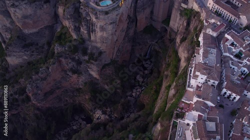 Aerial view of historic town on cliffside with bridge over Guadalevin River at sunset, Ronda, Spain.