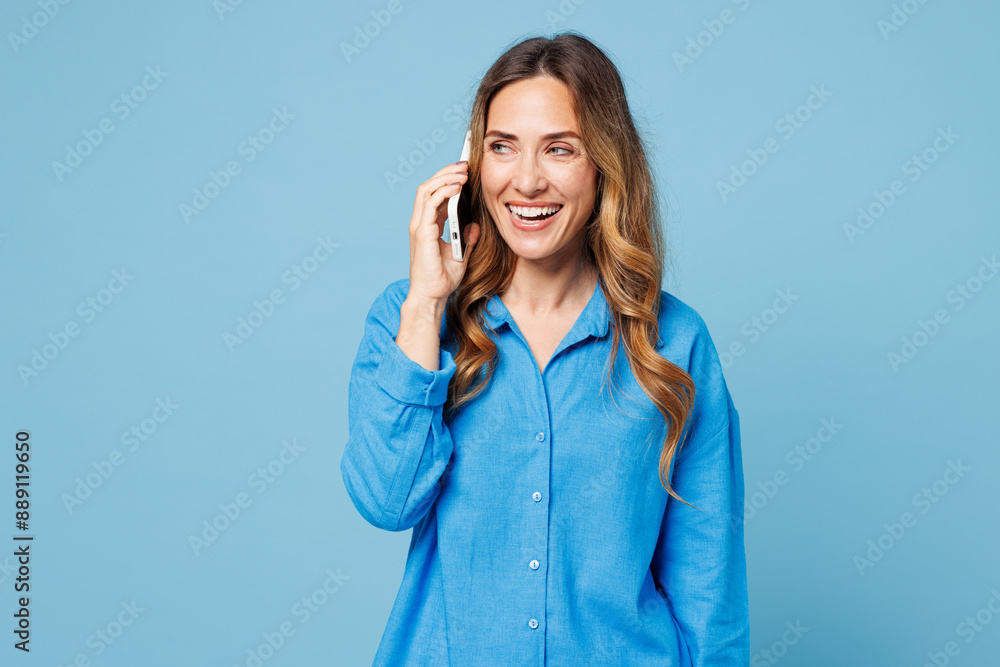 Young smiling happy cheerful woman 50s years old she wear shirt casual clothes talk speak on mobile cell phone isolated on plain pastel light blue cyan background studio portrait. Lifestyle concept. Young smiling happy cheerful woman 50s years old she wear shirt casual clothes talk speak on mobile cell phone isolated on plain pastel light blue cyan background studio portrait. Lifestyle concept.