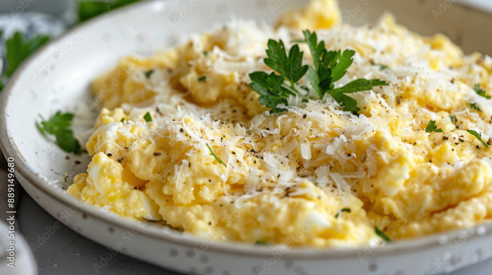 Creamy scrambled eggs topped with grated cheese and freshly ground pepper garnished with parsley on a white plate Creamy scrambled eggs topped with grated cheese and freshly ground pepper garnished with parsley on a white plate