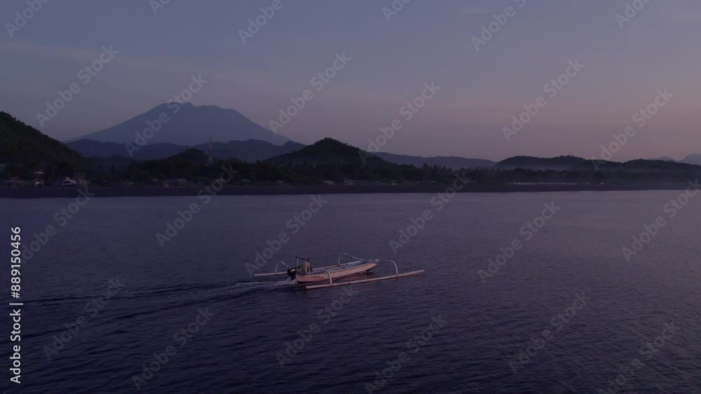 Aerial view of serene sunrise over calm sea with fishing boat and mountain, Karangasem, Bali, Indonesia. Aerial view of serene sunrise over calm sea with fishing boat and mountain, Karangasem, Bali, Indonesia.