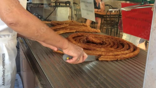 Unrecognizable man works in a traditional Spanish churreria cutting a 