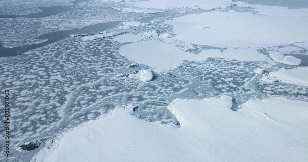 Antarctica coast frozen ocean surface aerial view. Ice floes, snow covered rocky land. Fly over untouched wilderness of Antarctic coastline wild nature landscape. South Pole travel and exploration Antarctica coast frozen ocean surface aerial view. Ice floes, snow covered rocky land. Fly over untouched wilderness of Antarctic coastline wild nature landscape. South Pole travel and exploration