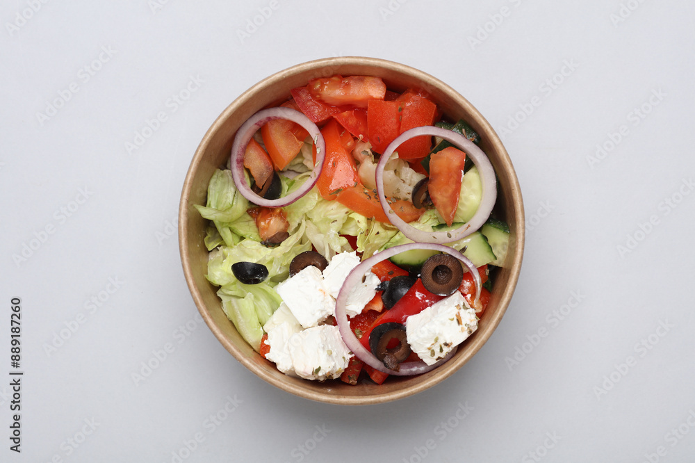 Greek salad in a disposable cardboard container on a gray background Greek salad in a disposable cardboard container on a gray background