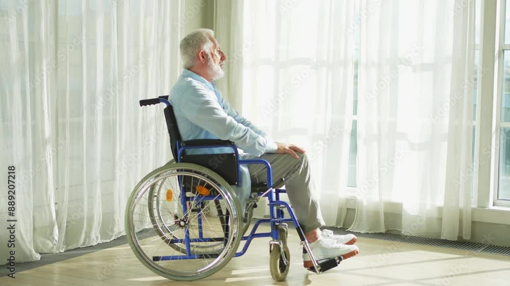 Sad senior man sitting in wheelchair looking out window in retirement home hospital. Old paralyzed man in chair for people with disability feel depressed. Lonely elderly sick man sitting on wheelchair Sad senior man sitting in wheelchair looking out window in retirement home hospital. Old paralyzed man in chair for people with disability feel depressed. Lonely elderly sick man sitting on wheelchair