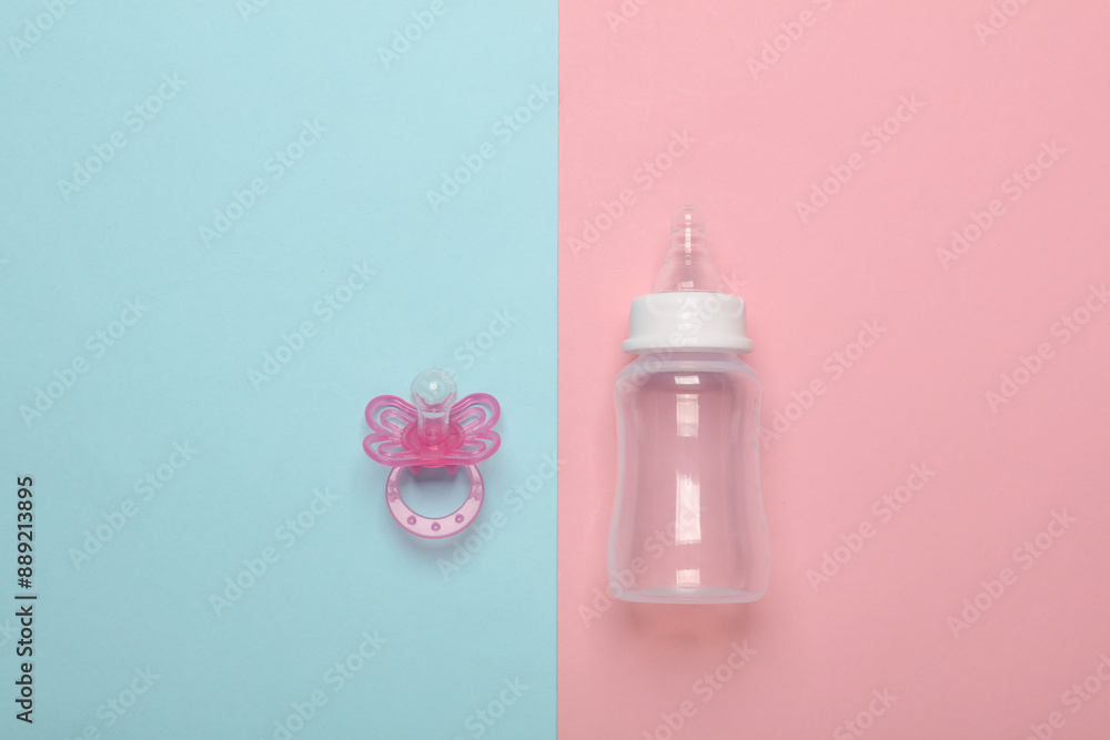 Bottle for feeding newborn and pacifier on a blue-pink background Bottle for feeding newborn and pacifier on a blue-pink background