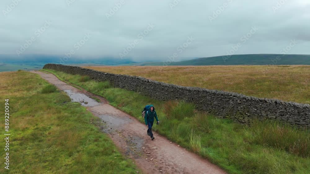 Hikers walking in Lake District near dry stone ancient wall, United Kingdom Hikers walking in Lake District near dry stone ancient wall, United Kingdom
