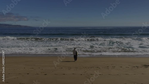 Sad isolate woman walks slowly backwards toward the sea. Loneliness, sadness, depression, suicide. Environmental photo