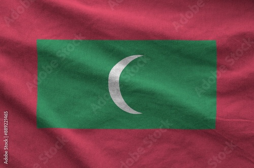 Maldives flag depicted on folded wavy fabric of old cloth close up photo