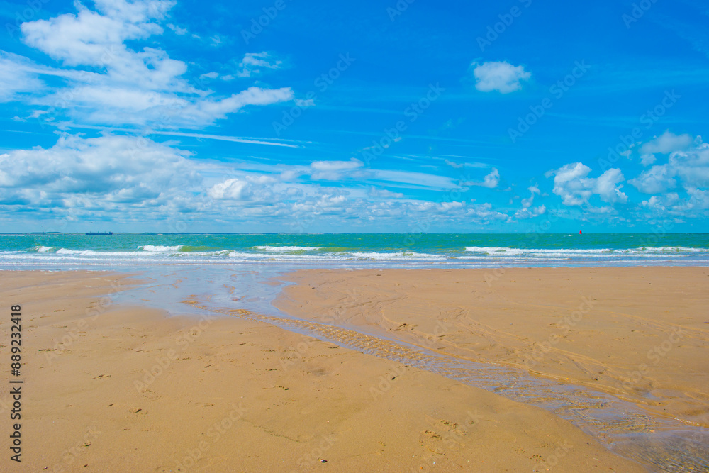 Sand beach along a sea under a blue cloudy sky in bright sunlight in summer, Walcheren, Zeeland, the Netherlands, July, 2024 Sand beach along a sea under a blue cloudy sky in bright sunlight in summer, Walcheren, Zeeland, the Netherlands, July, 2024