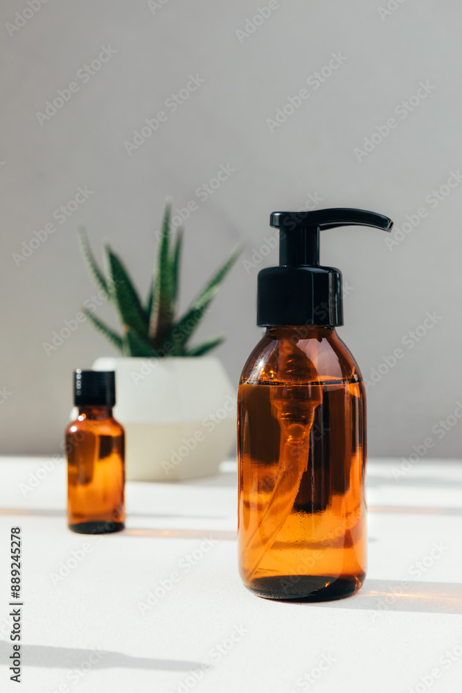 Set of natural cosmetics. Amber bottles with facial, bath liquid on a concrete background with natural bath sponge. Front view Set of natural cosmetics. Amber bottles with facial, bath liquid on a concrete background with natural bath sponge. Front view