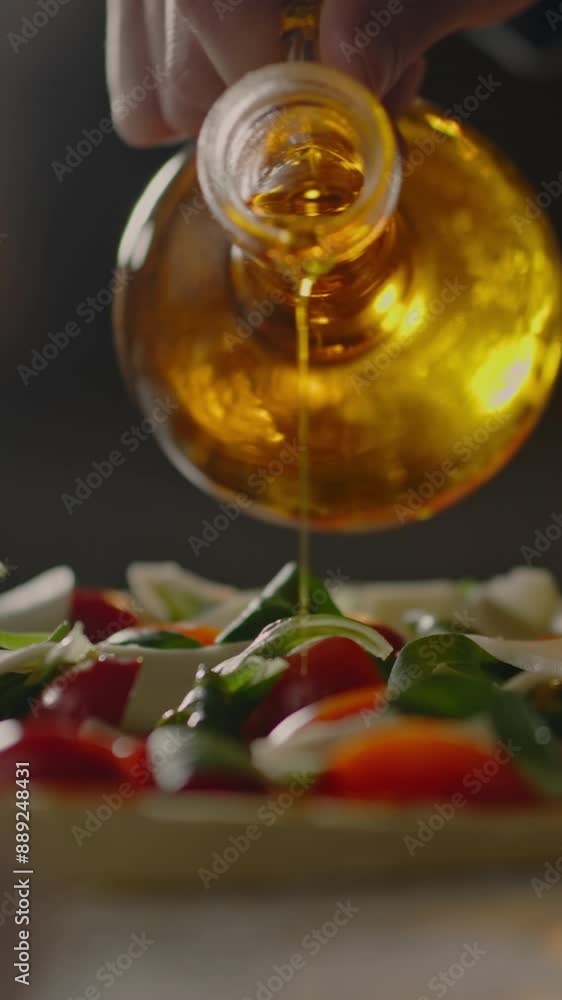 Vertical screen. In a pizzeria, a female baker carefully distributes the pizza toppings, adding olive oil. Long shot a young professional is busy in the culinary kitchen of a bakery Vertical screen. In a pizzeria, a female baker carefully distributes the pizza toppings, adding olive oil. Long shot a young professional is busy in the culinary kitchen of a bakery