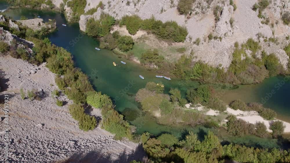 Aerial view of serene river with kayaks and canoes, surrounded by mountains and lush greenery, Zrmanja, Croatia. Aerial view of serene river with kayaks and canoes, surrounded by mountains and lush greenery, Zrmanja, Croatia.